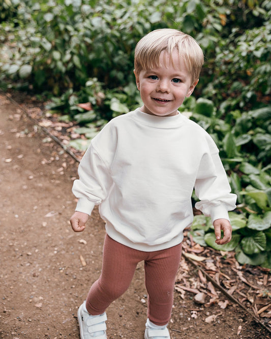 Toddler boy in terracotta ribbed leggings and soft cream sweatshirt